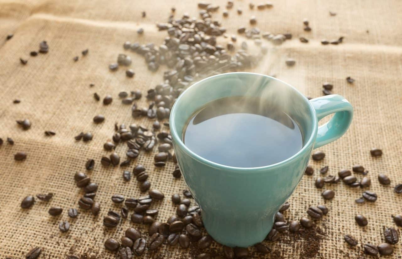 Una taza de café caliente con granos alrededor